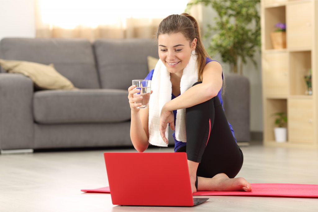 une élève boit un verre d'au après un cours de Pilates en ligne